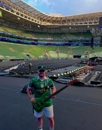 Músico com um baixo verde no palco de um estádio